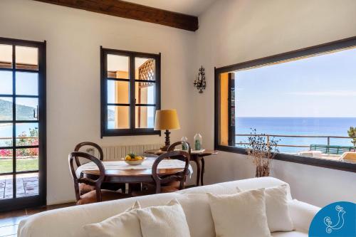 a living room with a table and a view of the ocean at Villa Anna - Charming dimora suspended over the sea in Geremèas
