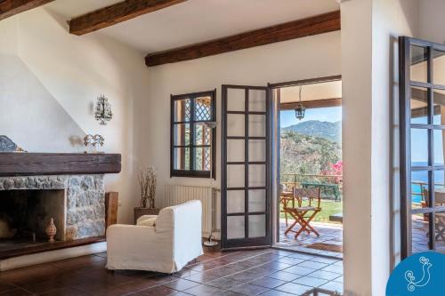 an open living room with a fireplace and a white chair at Villa Anna - Charming dimora suspended over the sea in Geremèas