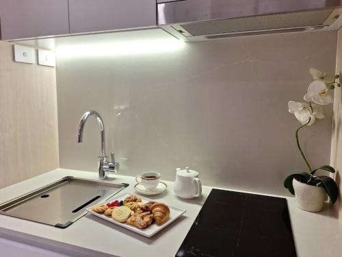a kitchen counter with a plate of pastries and a sink at Residence on Langley Park in Perth