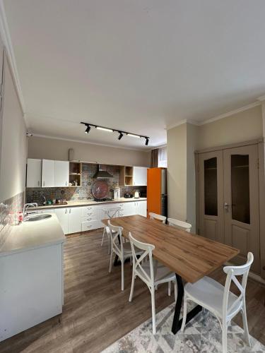 a kitchen with a wooden table and white chairs at Del Hostel in Almaty