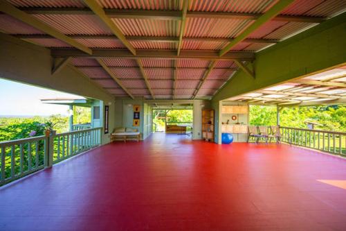 a large room with a balcony with a red floor at Kirpal Meditation and Ecological Center in Pahoa