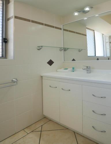 a white bathroom with a sink and a mirror at Merrima Court Holidays in Caloundra