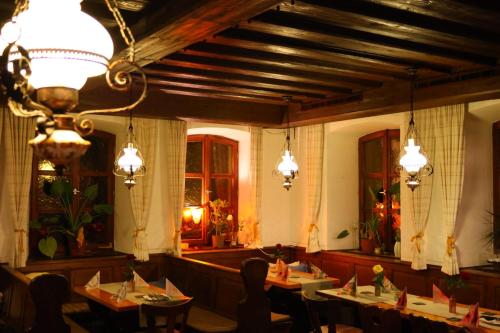 a dining room with tables and chairs and lights at Landgasthof Hotel Zum Roß Dorfgütingen in Feuchtwangen