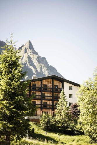 a large building with a mountain in the background at Sporthotel Bachmann in Gargellen