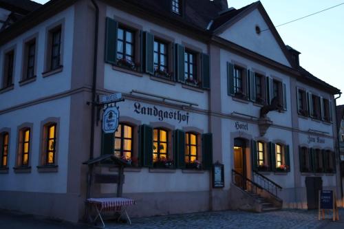 a white building with lights in the windows at Landgasthof Hotel Zum Roß Dorfgütingen in Feuchtwangen