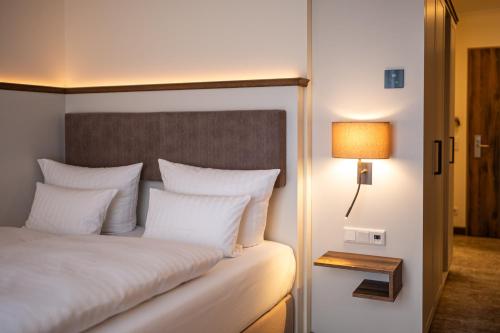 a bed with white pillows and a lamp next to it at Dorint Strandresort & Spa Ostseebad Wustrow in Wustrow