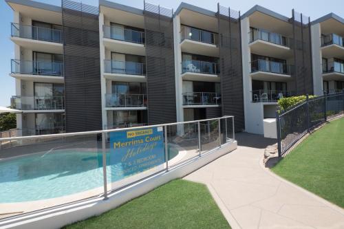 an apartment building with a swimming pool and a balcony at Merrima Court Holidays in Caloundra