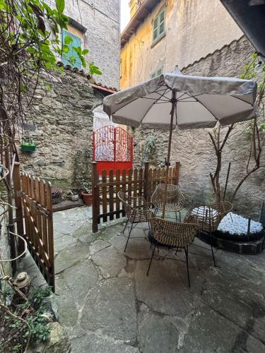a patio with a table and chairs and an umbrella at Appartamento in Centro Storico in Dorio