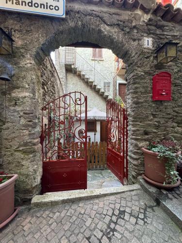 an archway with two red doors in a stone building at Appartamento in Centro Storico in Dorio