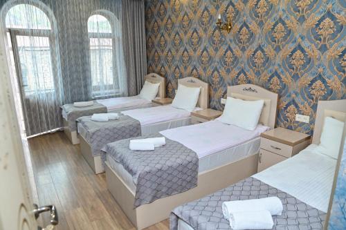 a room with four beds and a wall with wallpaper at Har-Mar Hotel in Goris