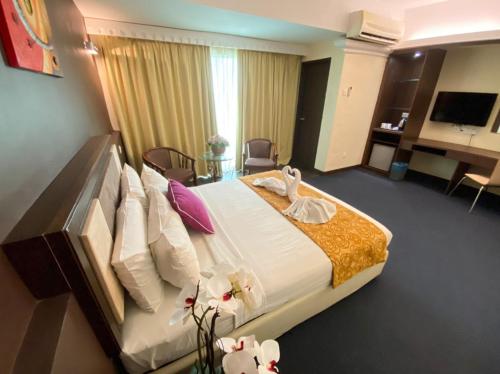 a hotel room with a large bed and a desk at Hotel Taiping Perdana in Taiping