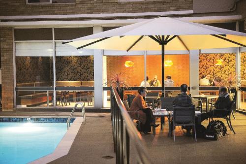 two people sitting at a table under an umbrella next to a pool at Royal Pacific Hotel in Sydney