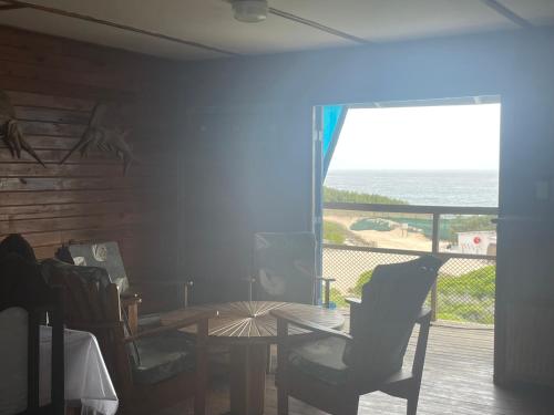a dining room with a table and a view of the ocean at Izmaan Lodge Pomene in Fombeni