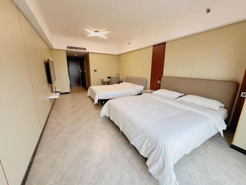 a hotel room with two beds and a flat screen tv at Linjiang Shangpin Apartment in Guangzhou