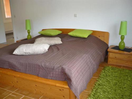 a wooden bed with two green pillows on it at Ferienwohnung beim Steinmetzmeister im Quarzwerk in Lautertal