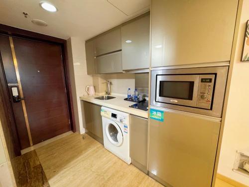 a kitchen with a washing machine and a microwave at Linjiang Shangpin Apartment in Guangzhou
