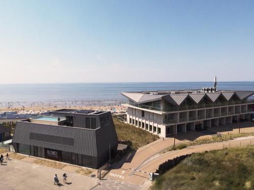 a building on the beach with the ocean in the background at Boutique Hotel Blendin Bloemendaal aan Zee in Bloemendaal Aan Zee