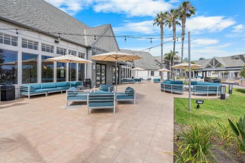 a patio with blue chairs and umbrellas in front of a building at Hilton San Diego/Del Mar in San Diego