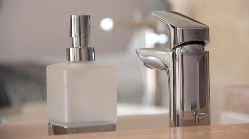 a close up of a soap dispenser next to a sink at Villapark Luxury Apartman Balatonfüred in Balatonfüred