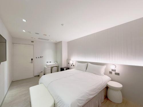 a white bedroom with a white bed and a desk at 在家行旅 南西館 in Taipei