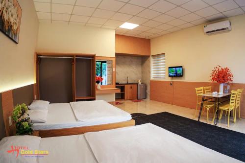 a room with two beds and a table and a kitchen at gold star homestay in Long Hai