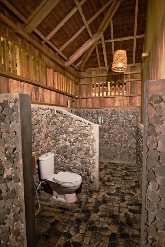 a bathroom with a toilet in a wooden building at Lavana Dive & Nature Resort in Unauna