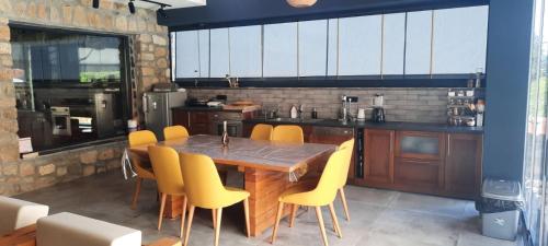 a kitchen with a wooden table and yellow chairs at Villa Obednikovski in Ljubojno