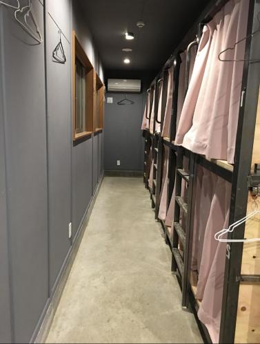 a long hallway with pink shirts on racks at Hostel und Kitchen GOTOBASE in Enokizu