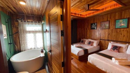 a room with two beds and a bathtub and a bedroom at The Floating Lake House in Ban Pracham Mai Bon