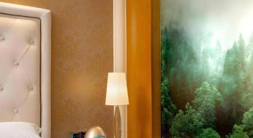 a bedroom with a bed and a lamp and a painting at Radegast Hotel CBD in Beijing