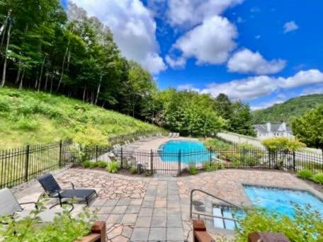 a backyard with a swimming pool and a fence at Swimming Pool Spa - Condo Mont Tremblant in Mont-Tremblant