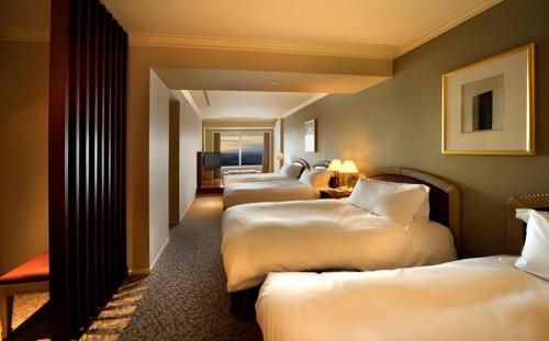 a row of four beds in a hotel room at Yokohama Royal Park Hotel in Yokohama
