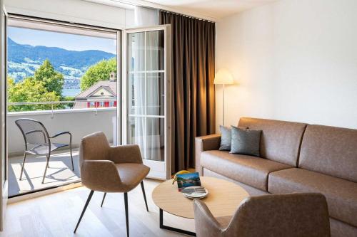 ein Wohnzimmer mit Couch und großem Fenster in der Unterkunft Seehotel Winkelried in Stansstad