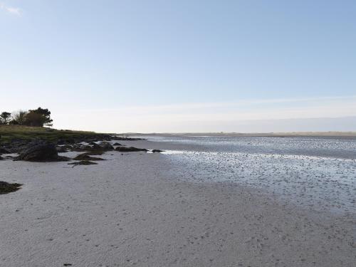 a beach with rocks and water in the foreground at Creagan Na Mara in Paible