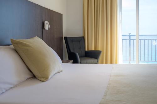 a bedroom with a bed with a pillow and a chair at Hotel Horitzó by Pierre & Vacances in Blanes