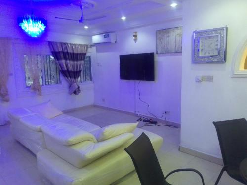 a purple room with a couch and a flat screen tv at MD guest house in Serekunda
