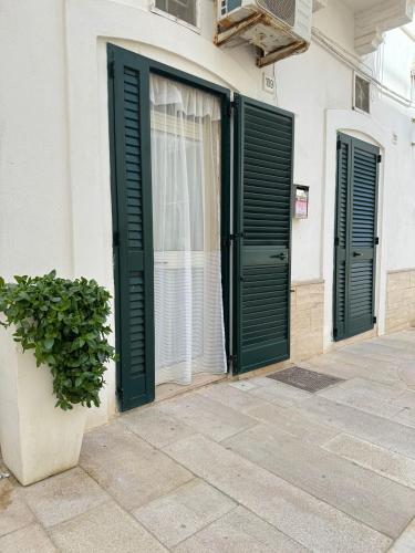 a building with green doors and a potted plant at Petali Rosa - Dimora Verde in Polignano a Mare