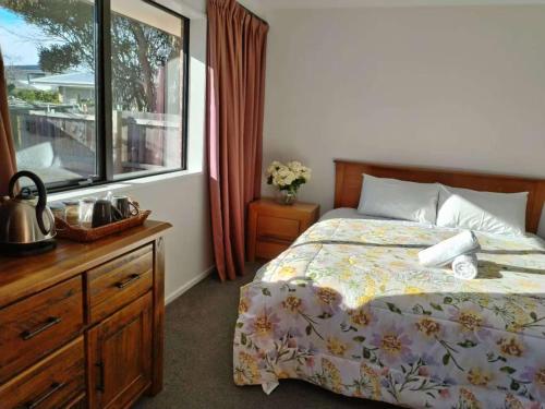 a bedroom with a bed with a dresser and a window at Cosy Sunny Bedroom Close to Airport in Christchurch