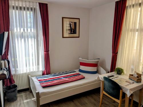 a room with a bed and a table and windows at Weisser Brunnen in Gotha
