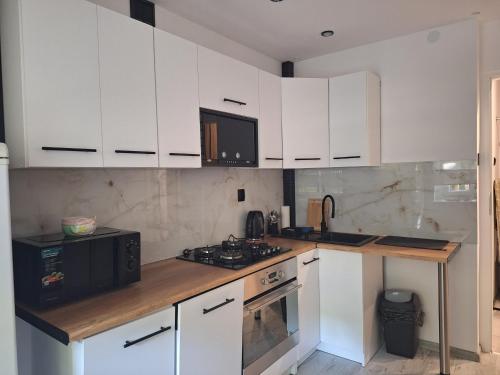 a kitchen with white cabinets and a black microwave at Apartament z jacuzzi w centrum Katowic in Katowice