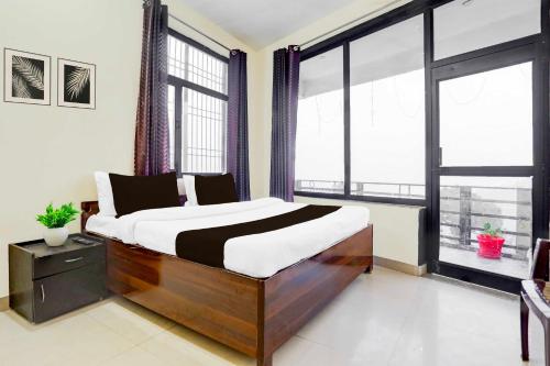 a bedroom with a large bed and large windows at Hotel O Bhowali Nainital Near Graphic Era Hill University in Nainital