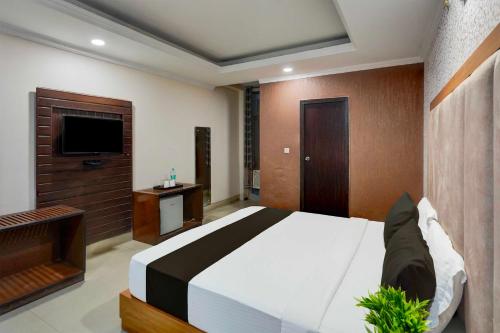 a bedroom with a large bed and a flat screen tv at Hotel O Awas Vikas Near Bus Stand in Rudrapur