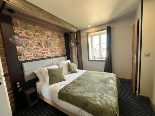 une chambre avec un lit et un mur de briques dans l'établissement La Suite du Bouquet, à Cosqueville
