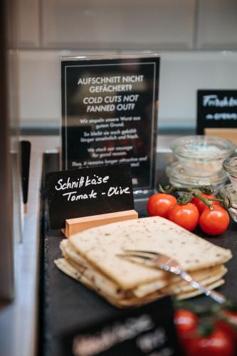 a table topped with cheese and tomatoes on a counter at Coffee Fellows Hotel Frankfurt Airport-Langen in Langen