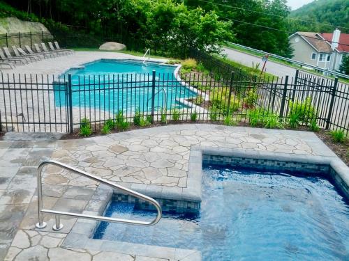 a swimming pool in a yard with a fence at Swimming Pool Spa - Condo Mont Tremblant 2 in Mont-Tremblant