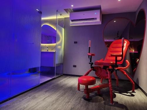a red chair in a room with a mirror at Goldinn Hotel in Taipei