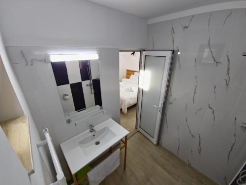 a white bathroom with a sink and a mirror at La Oprescu in Azuga