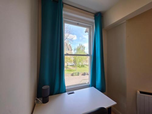 a room with a desk and a window with blue curtains at Modern 2 bedrooms apartment in Town centre in Ipswich