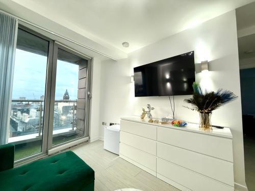 a living room with a tv and a large window at Winners of 2025 traveller Award, Elegant two bedroom city central apartment with Netflix & WiFi in Leeds