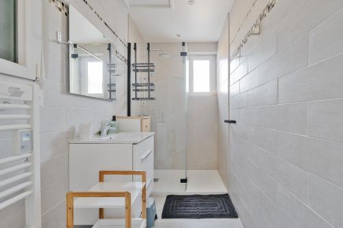 a white bathroom with a sink and a shower at Maison à 1300 m des plages in Saint Malo